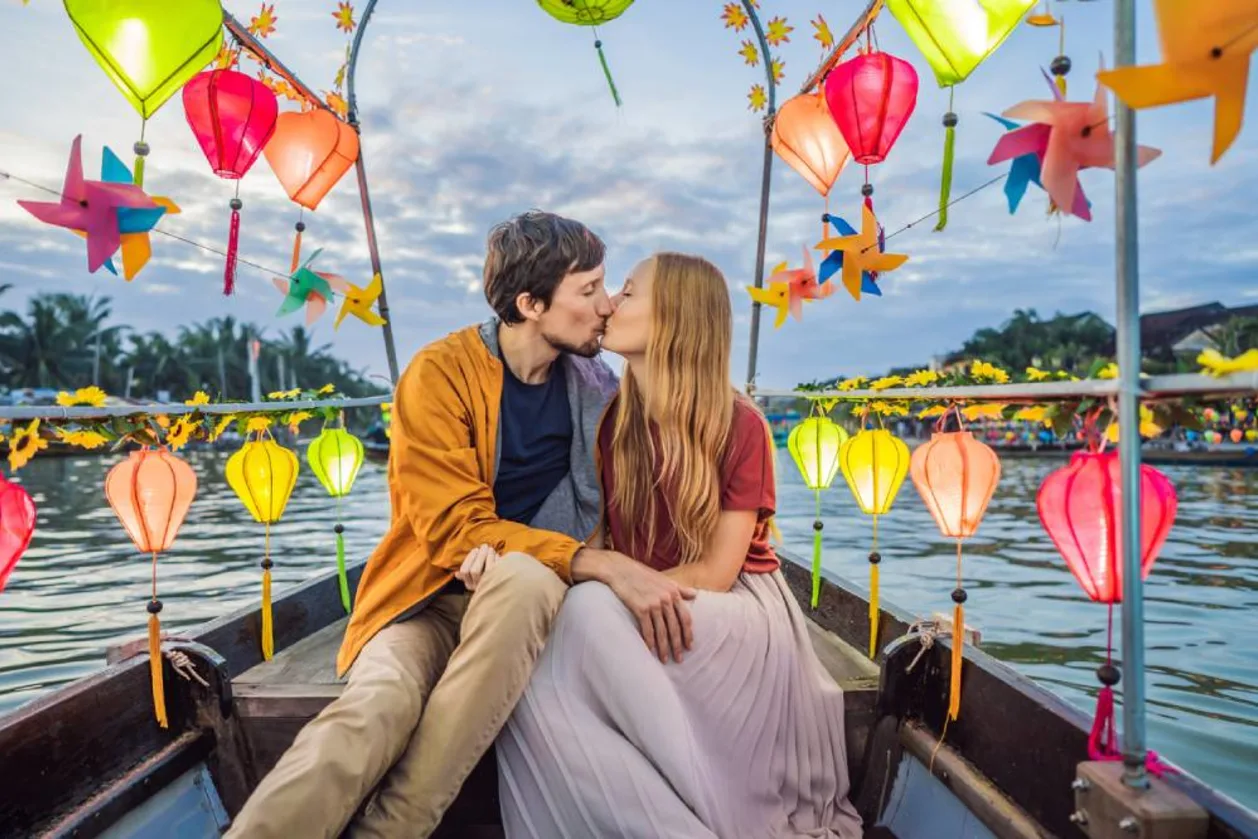 Couple kissing on boat with Hoi An in background